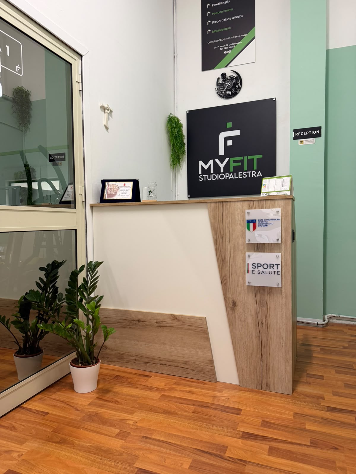 Reception di MYFIT Studio Palestra con insegna MyFit e parete verde salvia
